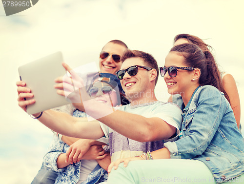 Image of group of smiling teenagers looking at tablet pc