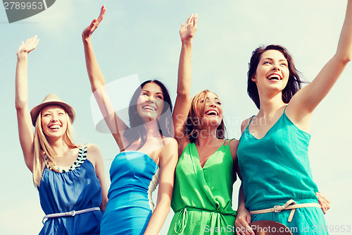 Image of girls walking on the beach and waivng hands