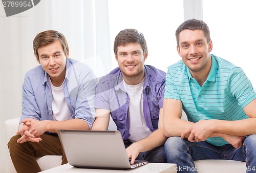 Image of smiling friends with laptop computer at home