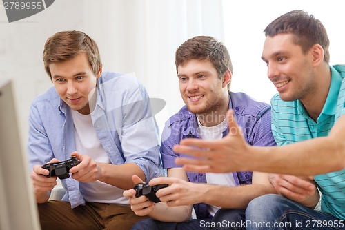 Image of smiling friends playing video games at home