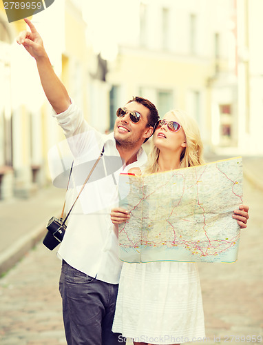 Image of smiling couple in sunglasses with map in the city