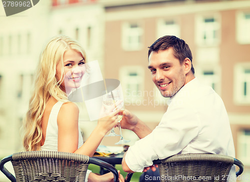 Image of smiling couple drinking wine in cafe