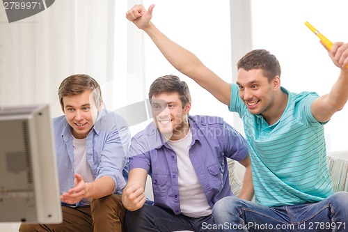 Image of happy male friends with vuvuzela watching sports