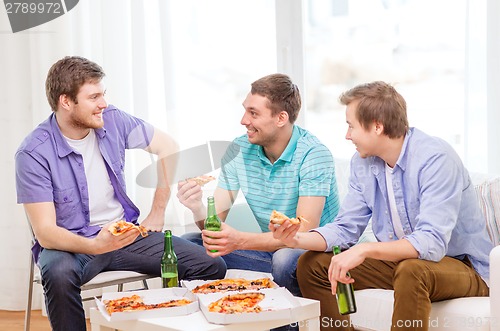 Image of smiling friends with beer and pizza hanging out