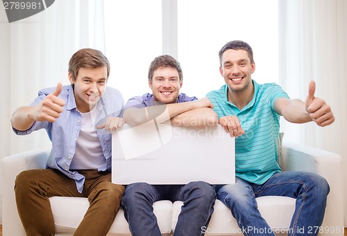 Image of smiling male friends holding white blank board