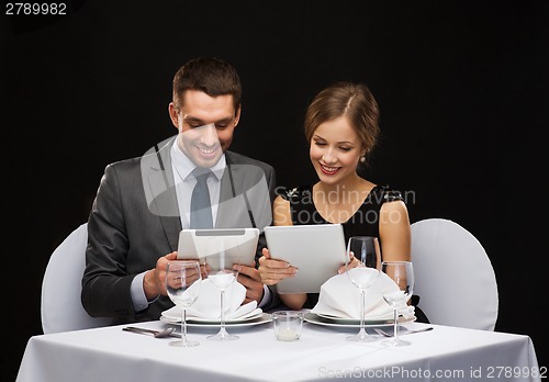 Image of couple with menus on tablet pc at restaurant