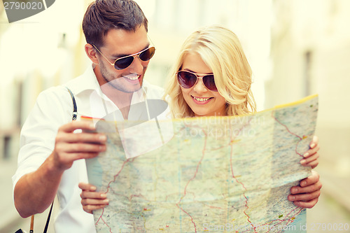 Image of smiling couple in sunglasses with map in the city