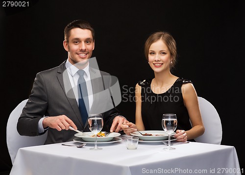 Image of smiling couple eating main course at restaurant