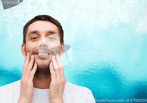 Image of beautiful smiling man touching his face