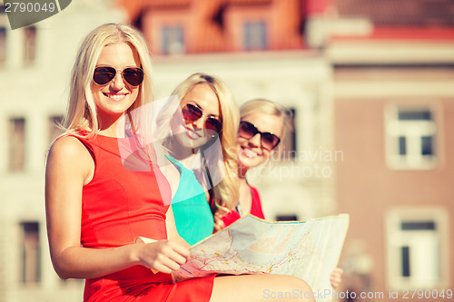 Image of beautiful three women with tourist map in the city