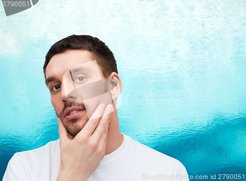 Image of beautiful calm man touching his face