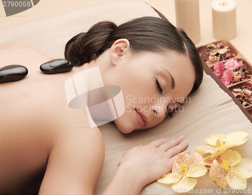 Image of asian woman in spa with hot stones