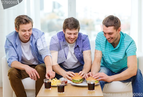 Image of smiling friends with soda and hamburgers at home