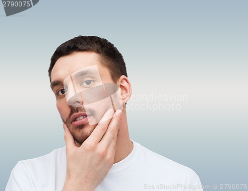 Image of beautiful calm man touching his face