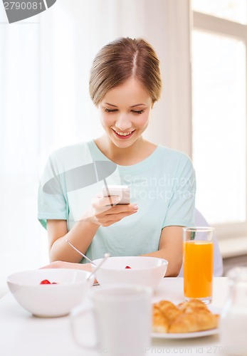 Image of smiling young woman with smartphone reading news