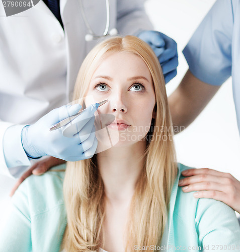 Image of plastic surgeon and nurse with patient