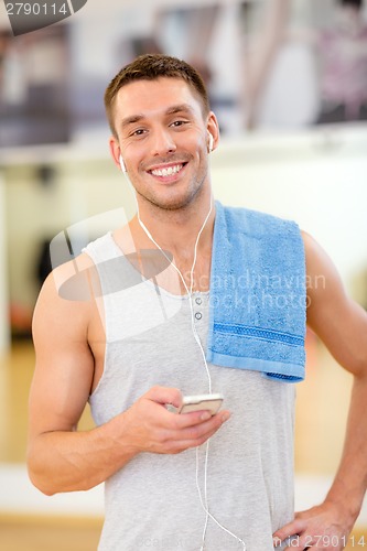 Image of young man with smartphone and towel in gym