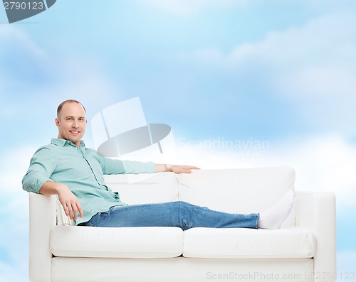 Image of smiling man lying on sofa