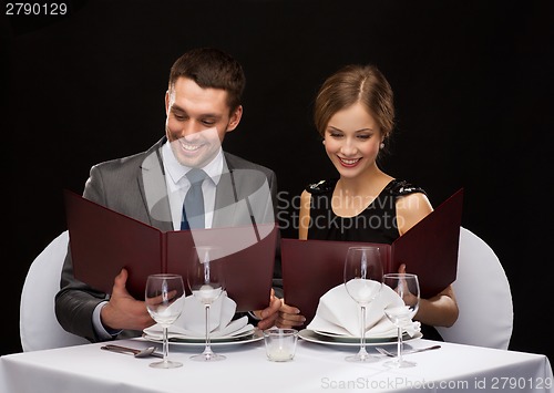 Image of smiling couple with menus at restaurant