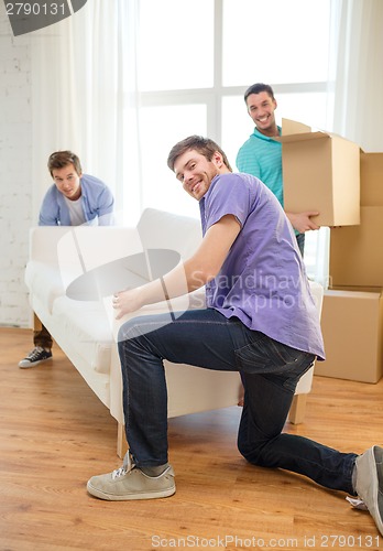 Image of smiling friends with sofa and boxes at new home