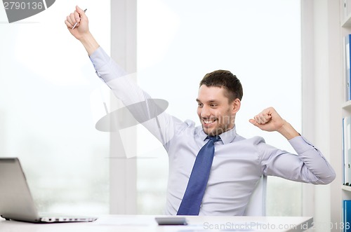 Image of smiling businessman with laptop and documents