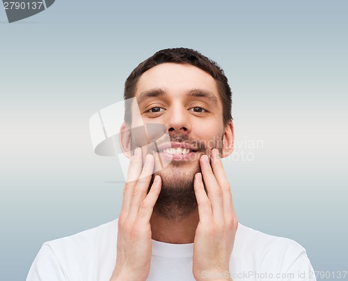 Image of beautiful smiling man touching his face