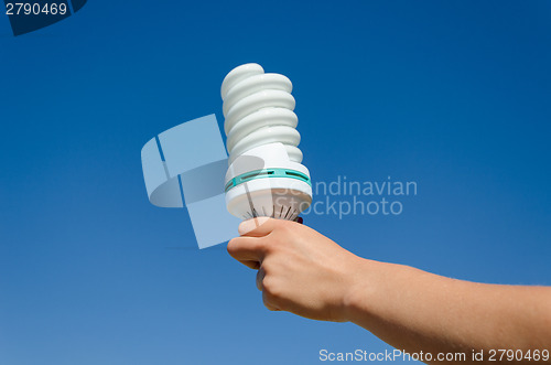 Image of hand hold ecology save bulb on blue sky background 