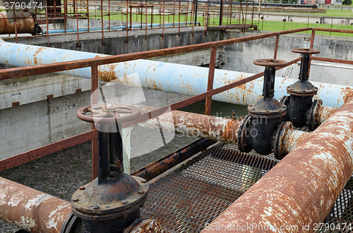 Image of Rusty big tap and pipes and water treatment liquid 