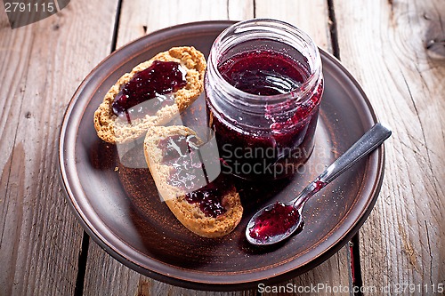 Image of black currant jam in glass jar and crackers