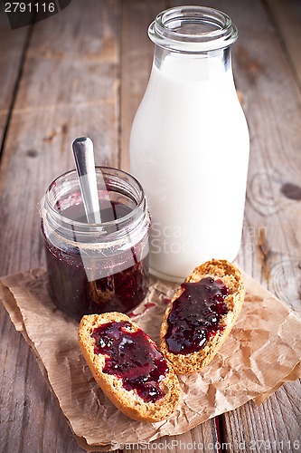 Image of black currant jam in glass jar, milk and crackers 