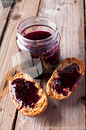 Image of black currant jam in glass jar and crackers