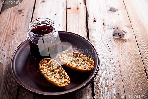 Image of black currant jam in glass jar and crackers