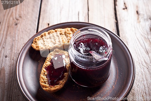 Image of black currant jam in glass jar and crackers