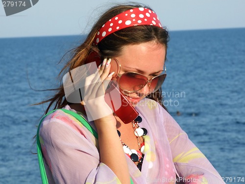 Image of The beautiful girl talks by a mobile phone on the sea