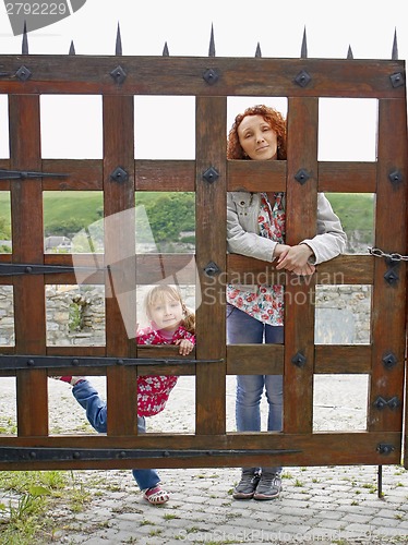 Image of Woman and a small girl behind a wooden gate