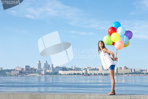 Image of Happy young woman with colorful balloons