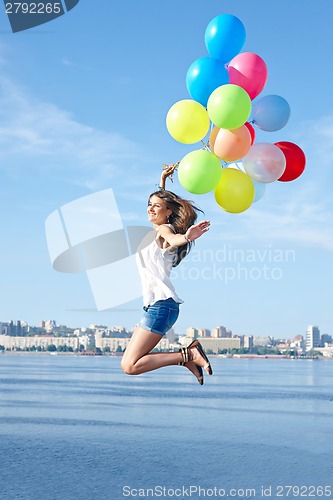 Image of Happy young woman jumping with colorful balloons