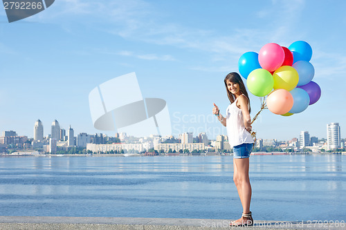 Image of Happy young woman with colorful balloons