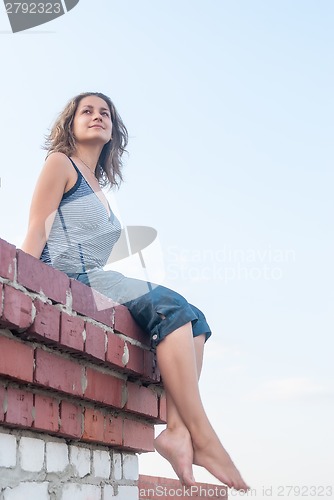 Image of Attractive girl sitting on roof