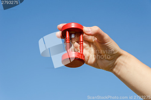 Image of red old hourglass in hand on blue sky background 