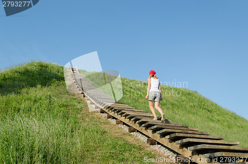 Image of tourist woman climb strairs on mound hill 