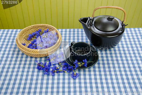 Image of freshly picked cornflower on basket clay tea set 