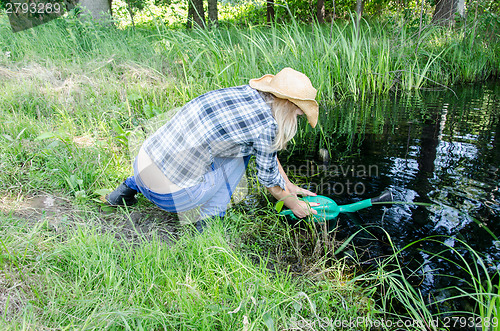 Image of Farm gardener girl draw water from pond 