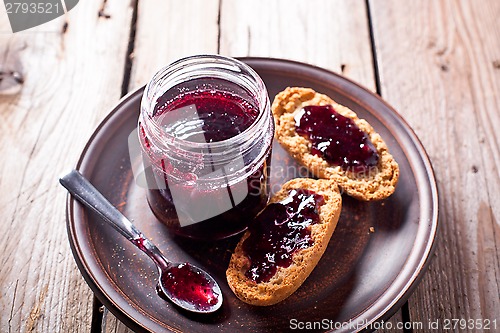 Image of black currant jam in glass jar and crackers