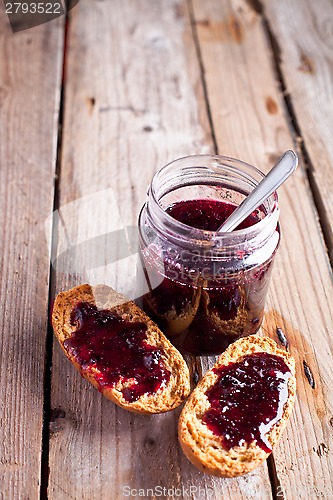 Image of black currant jam in glass jar and crackers 