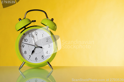 Image of Green alarm clock, close up. A yellow background