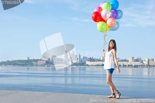 Image of Happy young woman with colorful balloons