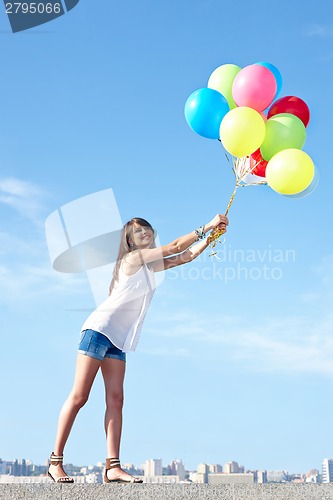 Image of Happy young woman flying away with balloons