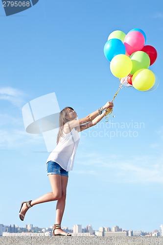 Image of Happy young woman flying away with balloons