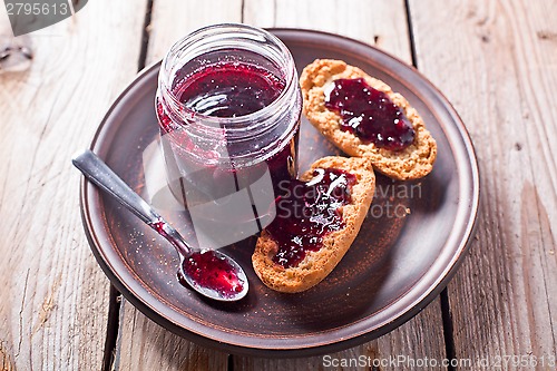 Image of black currant jam in glass jar and crackers